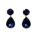Pair of royal blue faceted crystal teardrop earrings with round crystal tops and gold-tone settings on a white background.